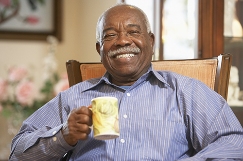 African American in blue shirt smiling and holding coffee cup